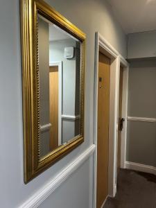 um espelho de ouro numa parede num quarto em Coronation Hotel em Londres