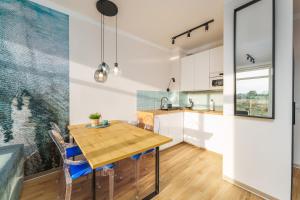 Il comprend une cuisine et une salle à manger avec une table et des chaises en bois. dans l'établissement Apartament Ultramarine II by HolidaySun, à Sianożęty