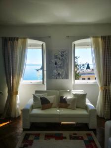a living room with a couch and two windows at APARTMENT VOLOSKO - 50m to the sea in Opatija