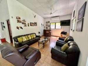 Sala de estar con 2 sofás de cuero y TV en Beautiful beach house in Los Cobanos El Salvador, en Los Cóbanos