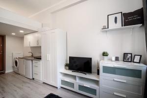a kitchen with white cabinets and a flat screen tv at Cozy Loft / Near Gates of Dawn / Free Netflix in Vilnius