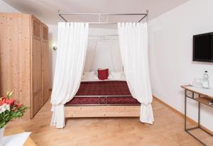 1 dormitorio con cama con dosel y cortinas en Gästehaus & Weingut PETH en Flörsheim-Dalsheim