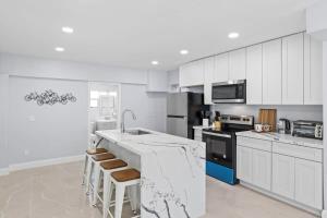 una cocina con armarios blancos y una barra con taburetes en Upgraded Ground Floor Residence on Buttonwood Ln w Bikes en Sanibel
