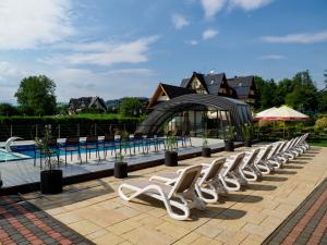 a row of white lounge chairs next to a pool at Hotel Liptakówka in Białka Tatrzanska