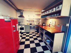 uma cozinha com um frigorífico vermelho e um piso em xadrez em Backpackers Luzern em Lucerna