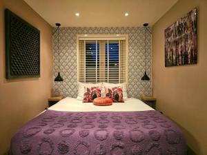 a bedroom with a large bed with a purple blanket at Zandvoort at Home I Free parking & Airco in Zandvoort