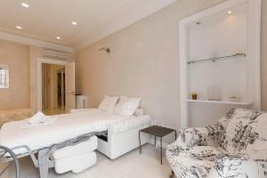 a white bedroom with a bed and a chair at Palais Miramar - Suite & A18 - Vue Mer - Croisette Emplacement Unique - 20M Plage - WIFI - Clim in Cannes