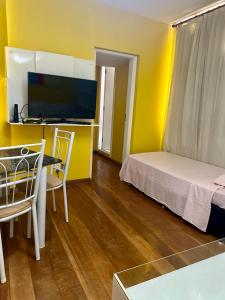 a small room with a bed and a table and a desk at Apartamento Avenida Atlântica in Rio de Janeiro