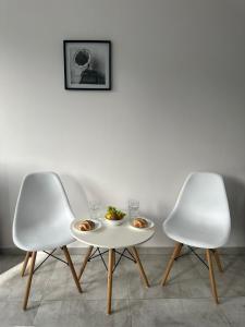 2 sillas blancas y una mesa con un bol de fruta en Kawalerka w Górach, en Wałbrzych