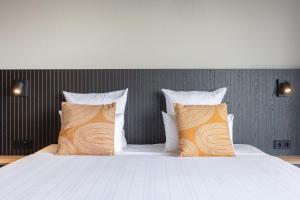 a bedroom with a bed with orange and white pillows at Leonardo Hotel IJmuiden Seaport Beach in IJmuiden