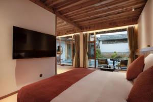 een slaapkamer met een groot bed en een flatscreen-tv bij Humble abode of happiness - Mountain View Wabi-sabi Lodge in Lijiang