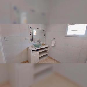 a white bathroom with a sink and a mirror at Corinto Tempo in Esquel