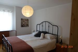 una camera da letto con un letto con lenzuola bianche e una lampada di APARTMA LINDAU a Lendava