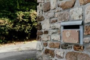 un cartello sul lato di un muro di pietra di L'Eden - Suite privative avec jacuzzi et sauna a Theux