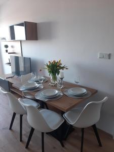 a dining room table with white chairs and a laptop at Apartament Browarna in Nowy Sącz