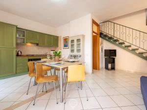 a kitchen with green cabinets and a table with chairs at Villasimius Coastal Nest in Villasimius +23 photos
