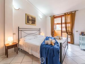 a bedroom with a bed with a blue blanket on it at Estay - Villasimius Coastal Nest - AirCon & Parking in Villasimius
