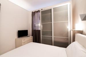 een slaapkamer met een wit bed en een televisie bij Santa Maria Maggiore Apartment in Barletta