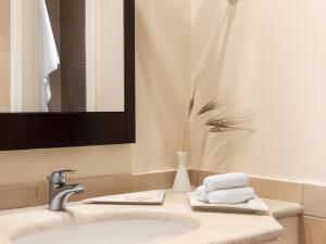 La salle de bains est pourvue d'un lavabo, d'un miroir et de serviettes. dans l'établissement Grecotel Filoxenia Hotel, à Kalamata