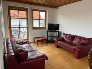 Sala de estar con 2 sofás de cuero y TV en Ferienplatzl 90m2 en Peißenberg