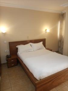 1 dormitorio con 1 cama grande con sábanas y almohadas blancas en MAKO PALACE Hôtel, en Bafoussam