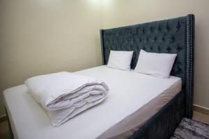 Bett mit schwarzem Kopfteil sowie weißer Bettwäsche und Kissen in der Unterkunft Tegera Homes in Kericho