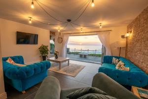 a living room with blue furniture and a view of the ocean at The White Cottage in Woolacombe