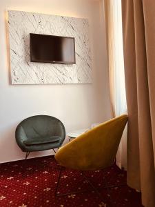 uma sala de estar com uma cadeira e uma televisão em Hotel Zava Boutique Central em Bucareste
