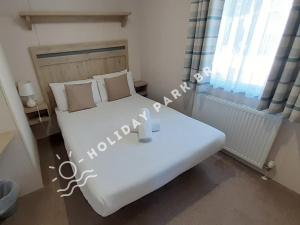 a bedroom with a large white bed and a window at Seagull Cove - 3bed at Seal Bay Resort in Selsey in Selsey +18 photos