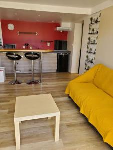 uma sala de estar com uma cama amarela e uma cozinha em La bastille 4 em Saintes