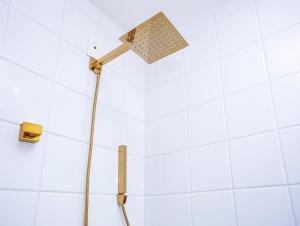 a shower head in a white tiled bathroom at Casa Hotel Sahy in Barra do Sahy