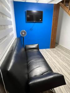 um sofá de couro preto num quarto com uma parede azul em Arzel's Tiny House em Mangatarem