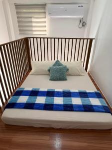 a bed with a blue and white plaid blanket at Arzel's Tiny House in Mangatarem