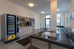 a restaurant with a refrigerator and a table and chairs at Aparthotel Oberfeld West München in Straßlach-Dingharting