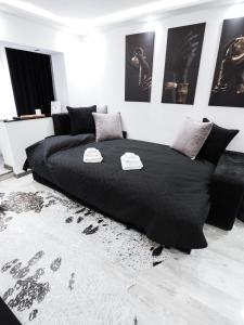 a bedroom with a black bed with two towels on it at Black&White mountain - ADULTS ONLY in Petroşani