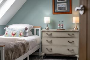 a bedroom with a bed and a dresser with two lamps at No7 Drummond Street, 2 bedrooms, Comrie in Comrie