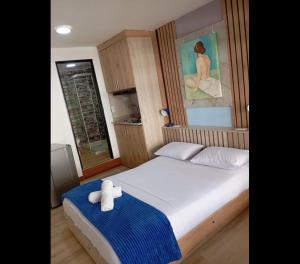a bedroom with a white bed with a blue blanket at Hotel Lares 70 Laureles in Medellín