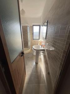 La salle de bains est pourvue d'un lavabo et de toilettes. dans l'établissement A&K Apartment, à Shkodër