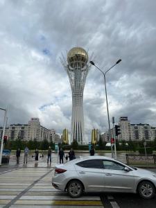 a car parked in front of a large tower at 224 Чудесный вид на Байтерек с 2 диванами и большой кроватью для 1-5 чел in Astana