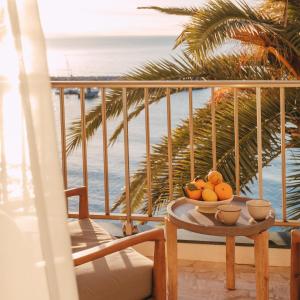 a bowl of fruit on a table on a balcony with the beach at Soleil Riviera Apartament Côte d’Azur in Roquebrune-Cap-Martin