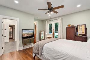 a bedroom with a bed and a flat screen tv at The Grove Cottage - Downtown Springdale in Springdale