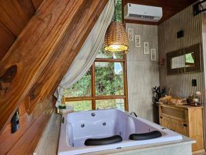 uma grande banheira branca num quarto com uma janela em Sítio Família Cherba - Cabana do Lago em Videira