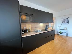 a kitchen with black cabinets and a sink at *TOP* Große, moderne & zentrale Wohnung 3 Schlafzimmer - Nähe zu Köln: Dom, Messe, Flughafen, Lanxess-Arena in Bergisch Gladbach