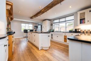 a large kitchen with white cabinets and wooden floors at Bank Farm House - Stunning House & Gardens in Shenstone