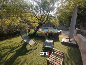 a yard with two chairs and a bench and a pool at Villa les Cigales - 8 couchages in Carry-le-Rouet
