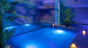 a swimming pool with blue lights in a room with plants at Grand Hotel Zagreb in Zagreb