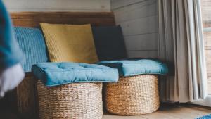 two wicker baskets with blue pillows sitting next to a window at L'Escale Zen - Tiny House (Jacuzzi/Sauna) in Theux