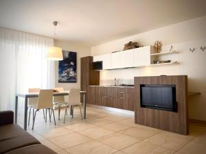uma sala de estar com uma televisão e uma mesa de jantar em Residenza Roma Marina em Sottomarina