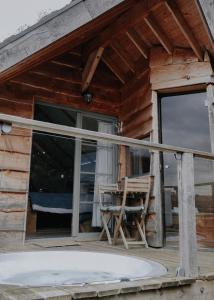 eine Veranda eines Blockhauses mit einem Tisch und einem Stuhl in der Unterkunft L'Escale Zen - Tiny House (Jacuzzi/Sauna) in Theux