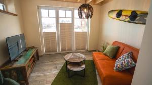 ein Wohnzimmer mit einem orangenen Sofa und einem TV in der Unterkunft Fischerhäuschen am Kurpark in Neuharlingersiel